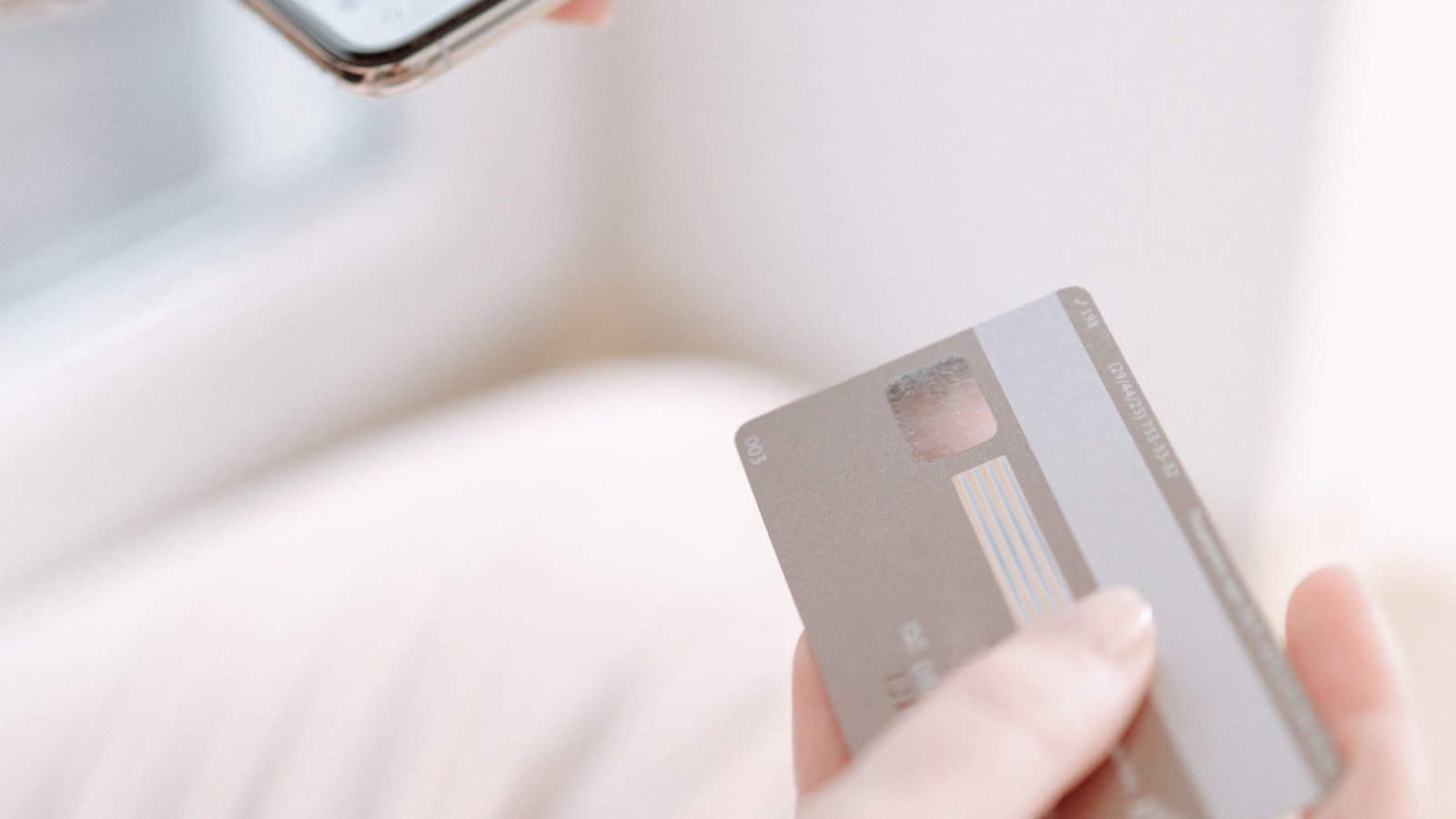 Hands using a smartphone and payment card while reviewing a digital purchase.