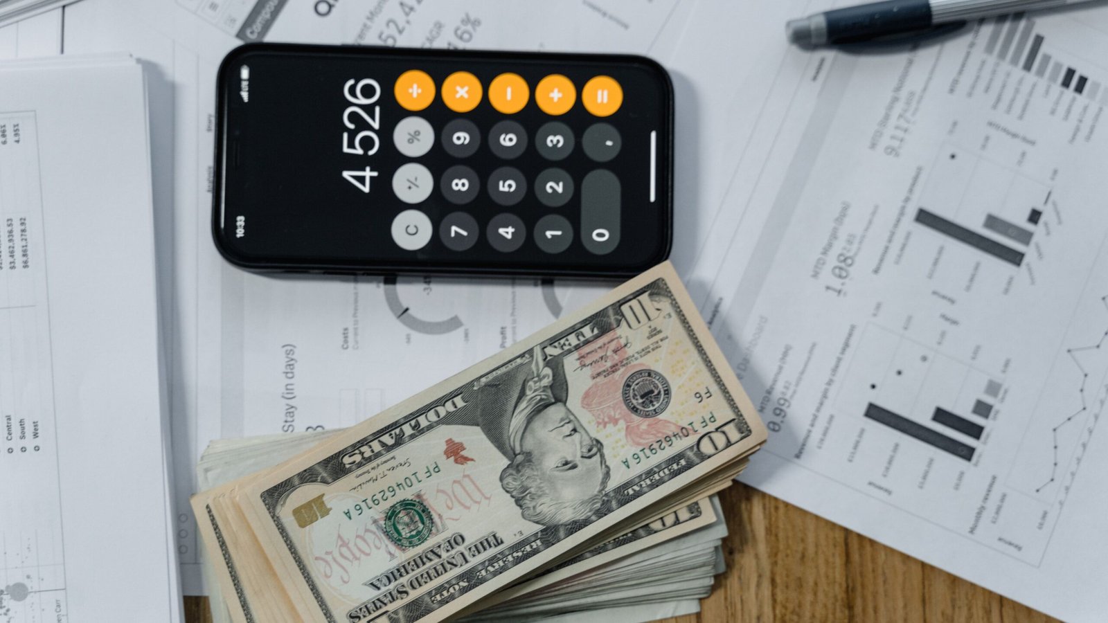 Calculator, U.S. dollar banknotes and financial papers used to assess a small loan.