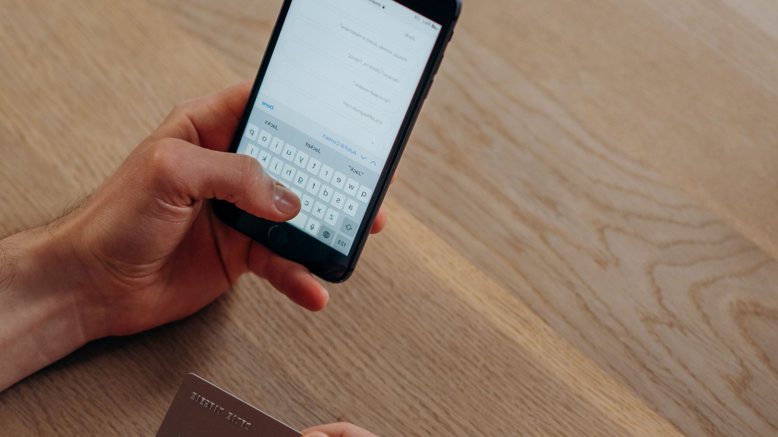 Hands holding a smartphone and payment card to manage cashless spending.