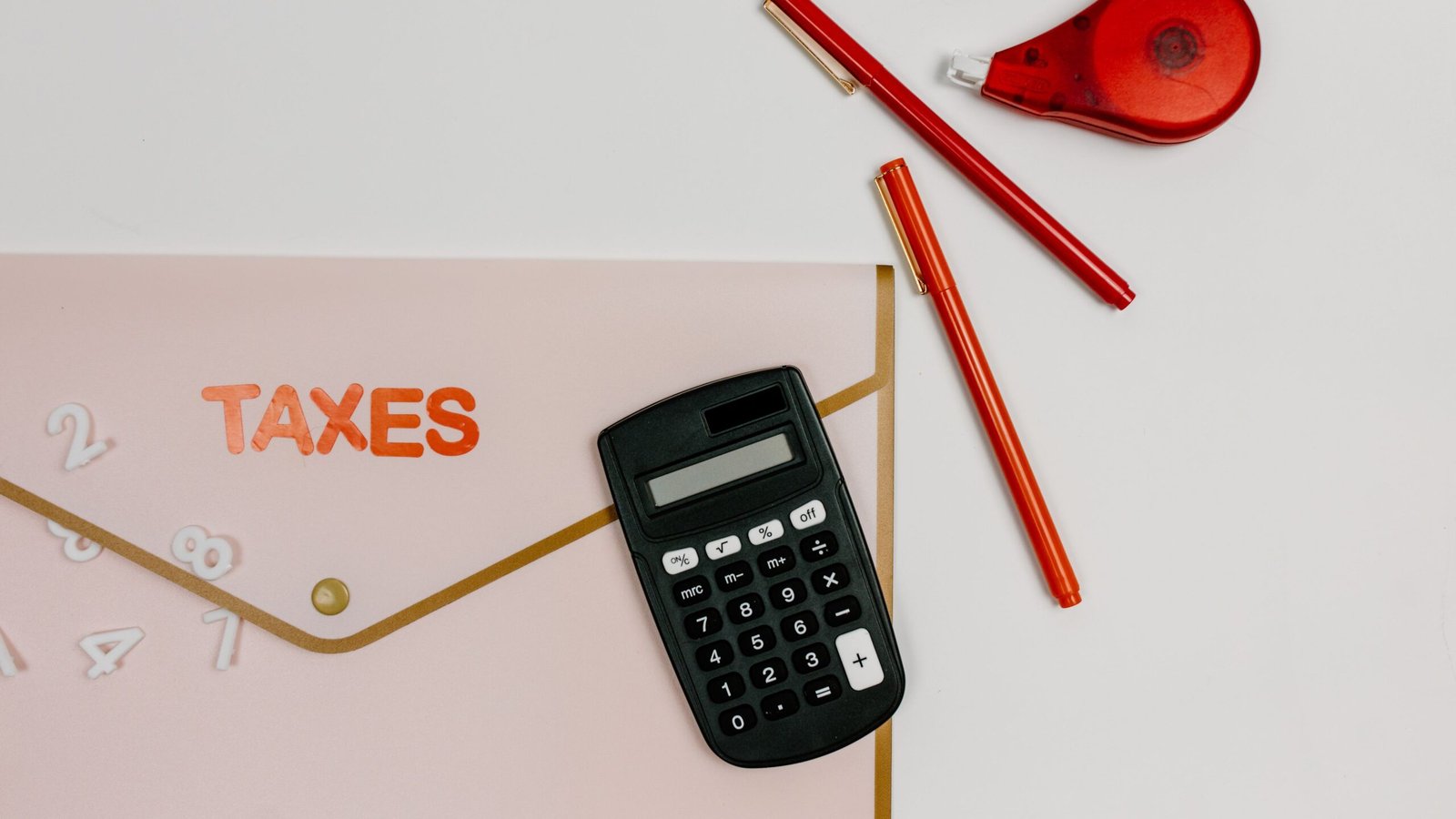 Calculator, folder of tax records and pens arranged for tax preparation.