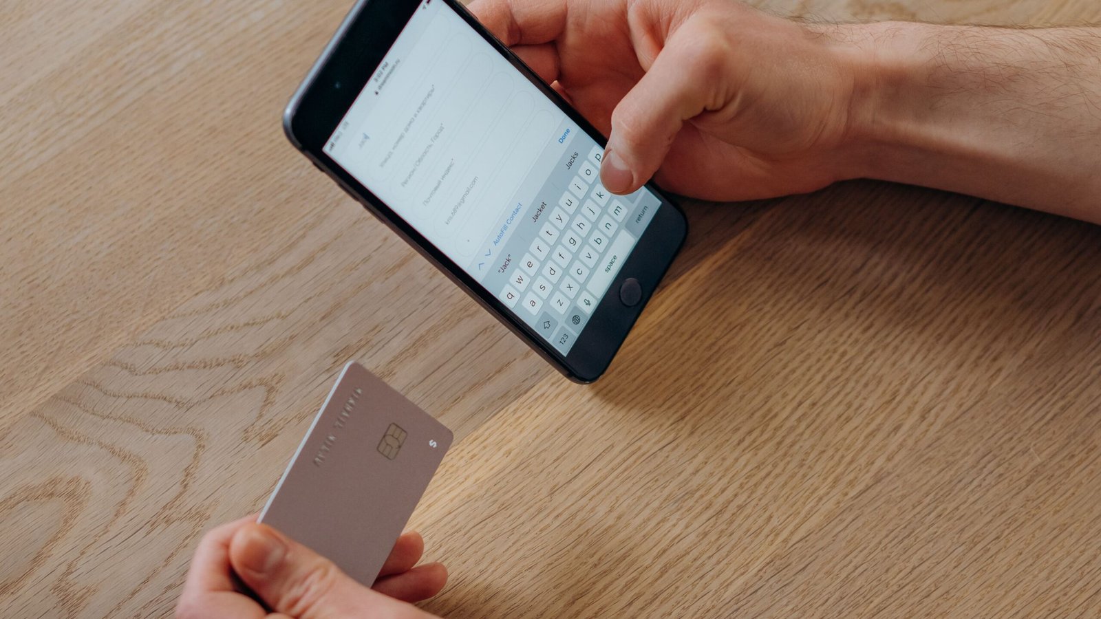 Hands holding a credit card and smartphone while checking an online payment.