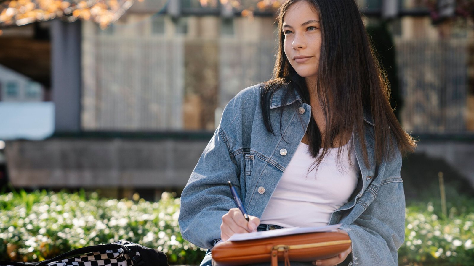 College student writing notes while preparing for a financial aid application