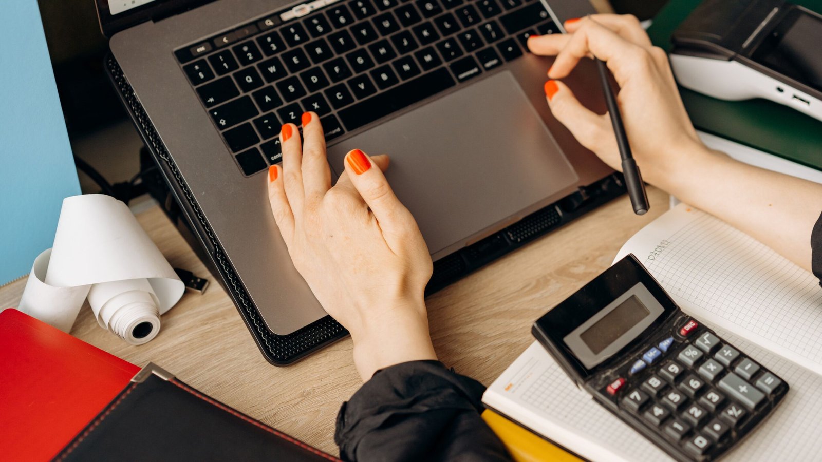 Hands working on a laptop at an office desk while preparing a cash-flow forecast