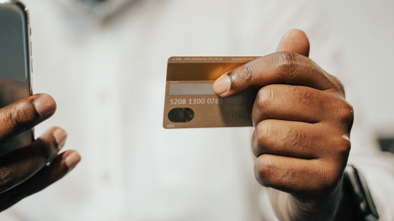 Close-up of hands holding a smartphone and a payment card.