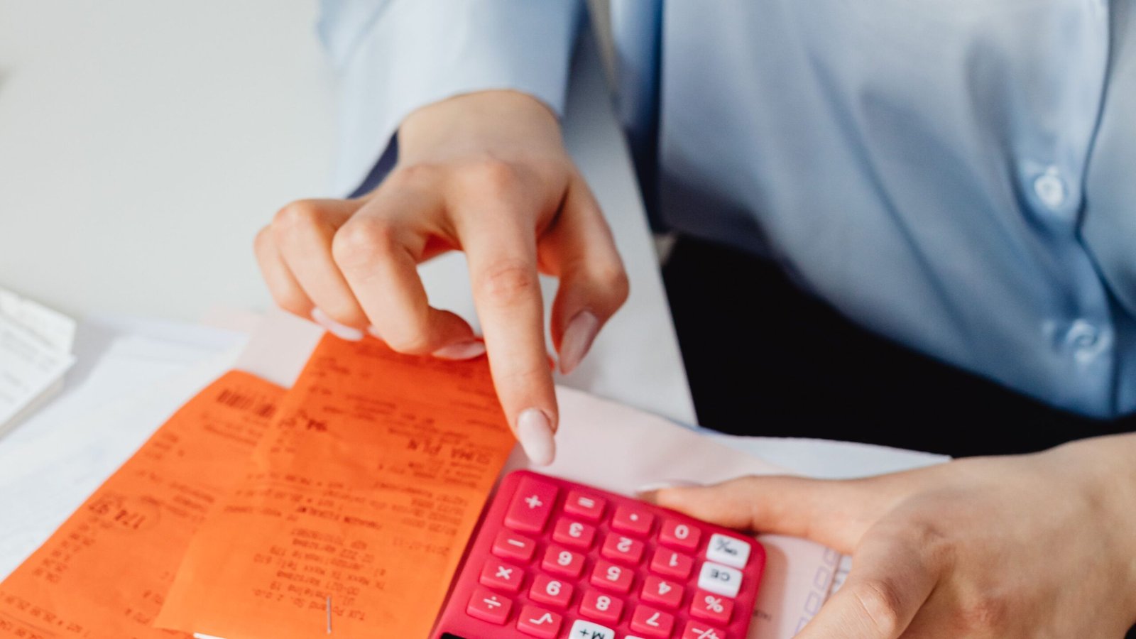 Hands reviewing receipts and using a calculator to classify expenses.