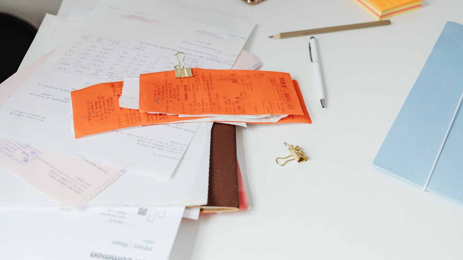 Physical receipts and invoice paperwork spread on a desk for payment verification