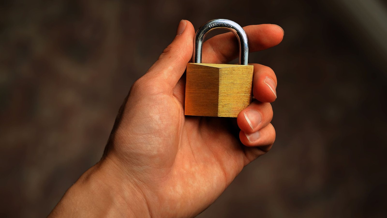 A hand holding a brass padlock to represent protecting financial information on lending apps.