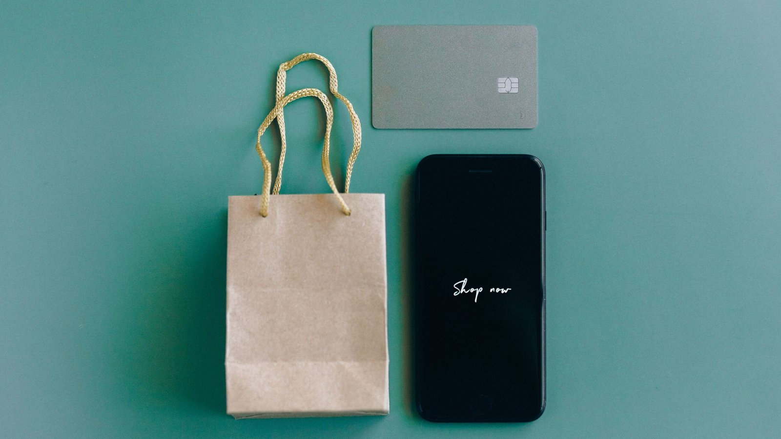 Smartphone, shopping card and payment items on a green surface illustrating everyday digital payments.