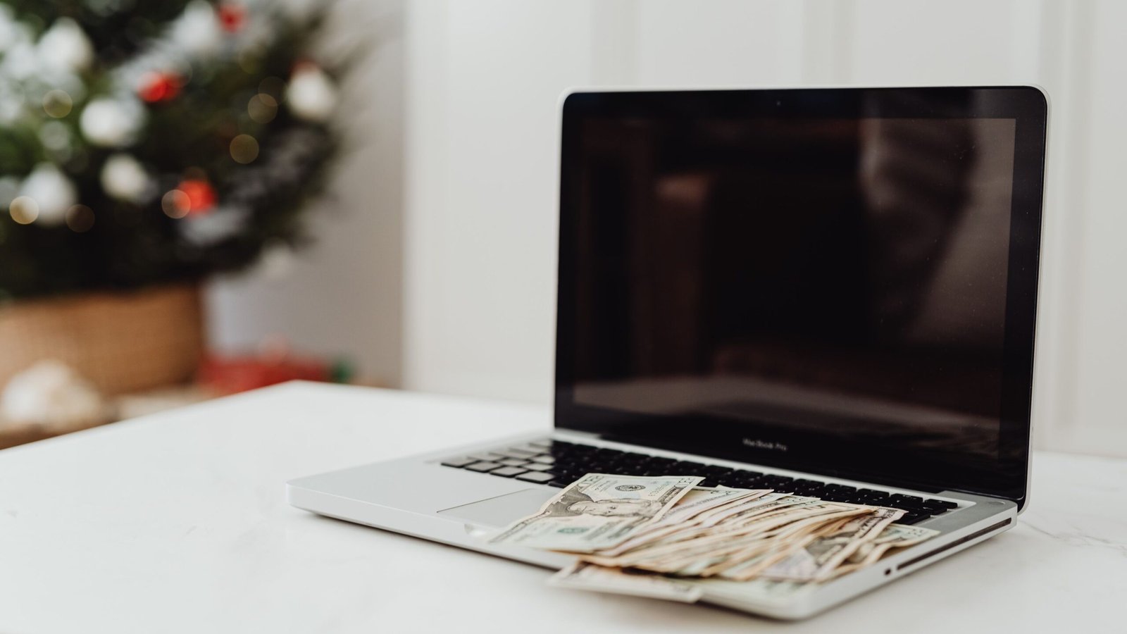 Laptop and money on a desk illustrating business cash received versus accounting profit