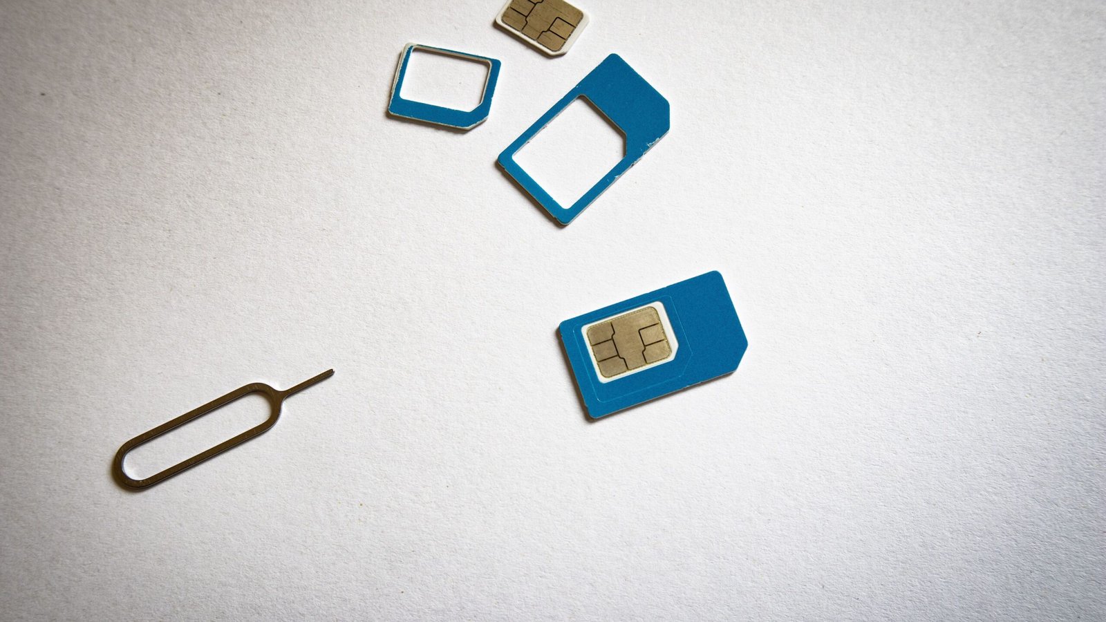 Actual SIM card and ejector tool photographed on a white surface illustrating SIM swap risks