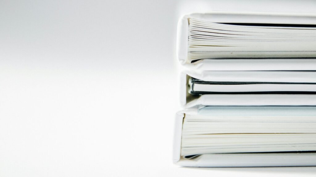 A stack of thick white binders with the page edges visible.