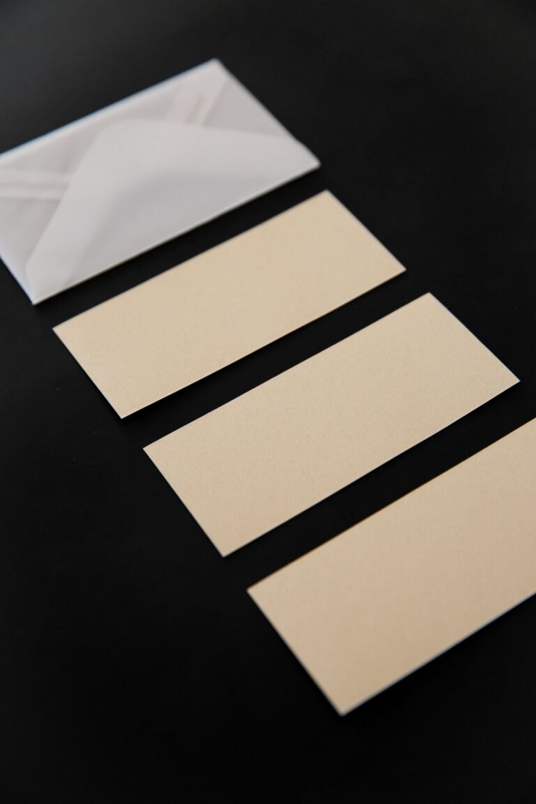 An unmarked envelope beside three blank cards on a dark surface.