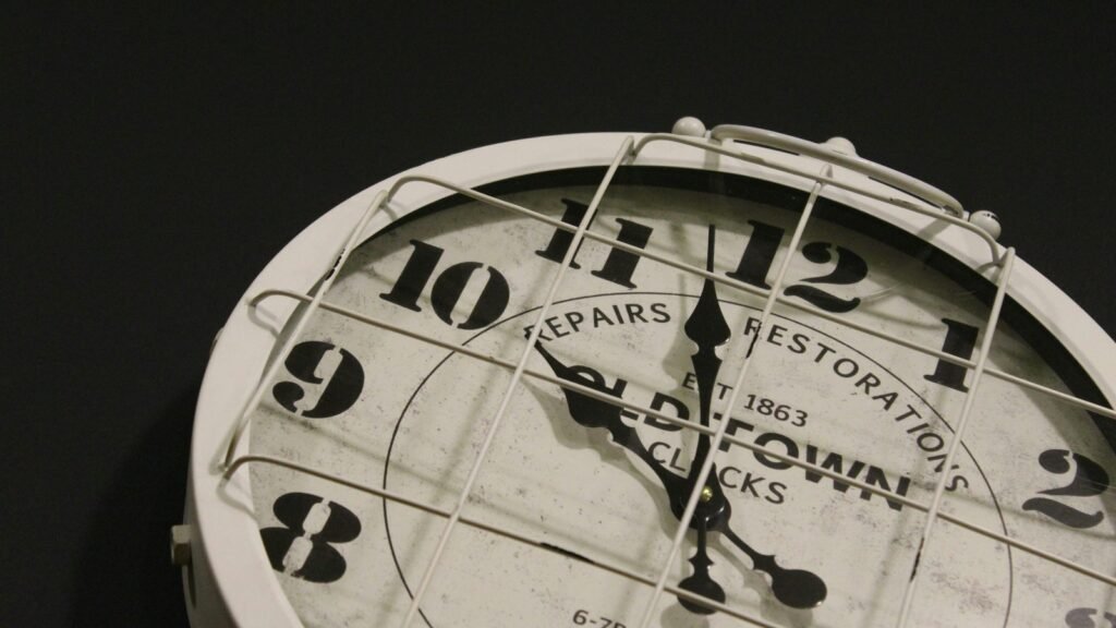 Close-up of a white analog clock behind a wire guard.
