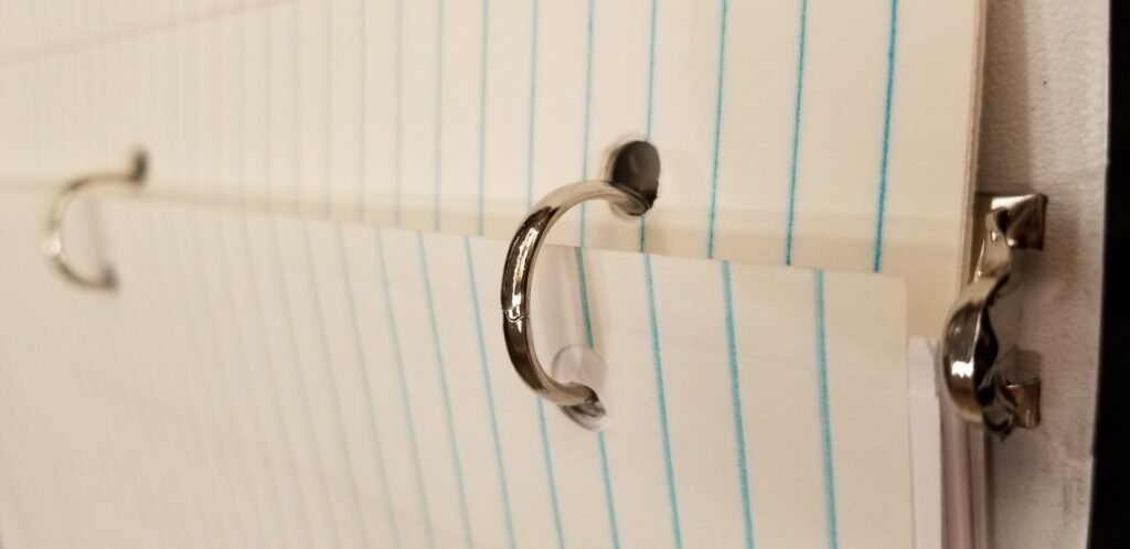 Close-up of metal binder rings holding blank lined paper.