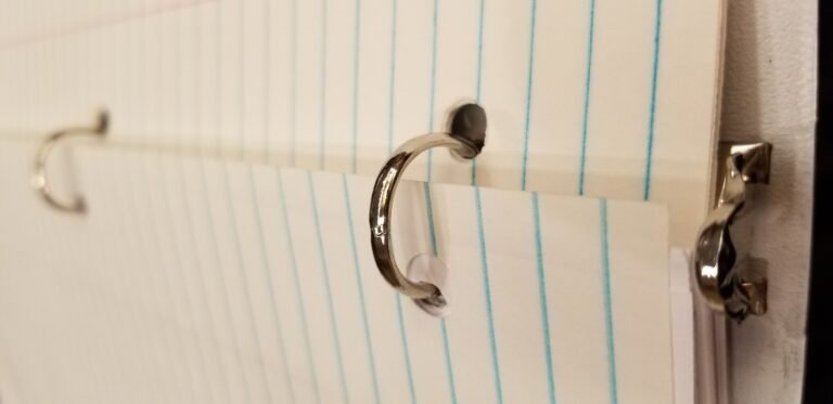Close-up of metal binder rings holding blank lined paper.