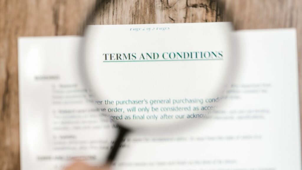 Magnifying glass over the words Terms and Conditions on a paper document.
