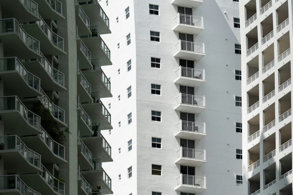 White apartment-building facades with rows of windows and balconies in sun and shade.