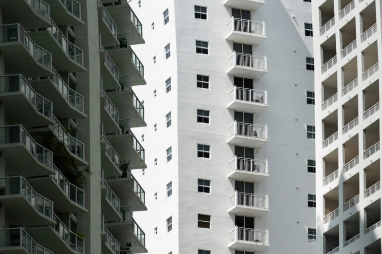 White apartment-building facades with rows of windows and balconies in sun and shade.