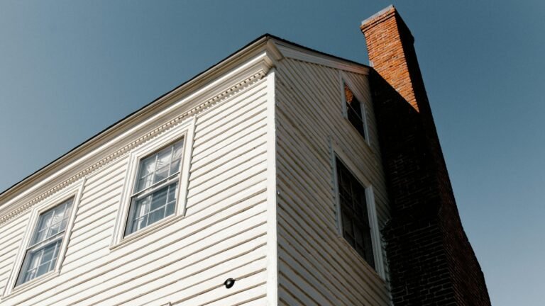 A white house with a brick chimney viewed from below.