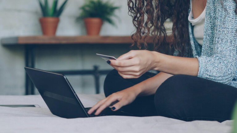 An adult holding a card while using a tablet at home.