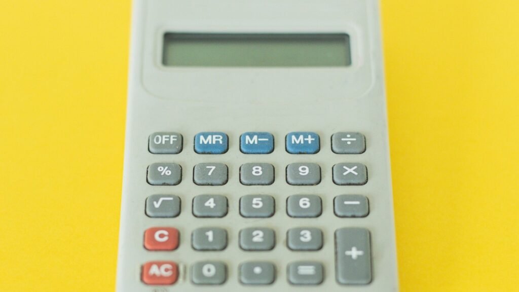 A gray calculator with an empty display on a yellow background.