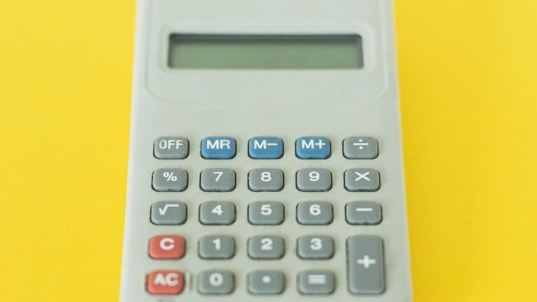 A gray calculator with an empty display on a yellow background.