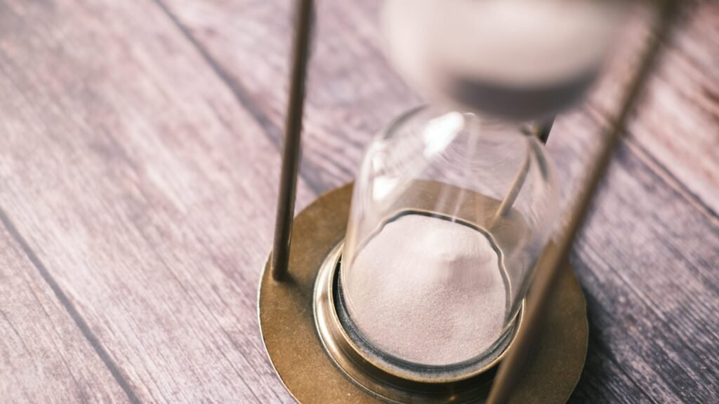 Close-up of an hourglass on a wooden surface.