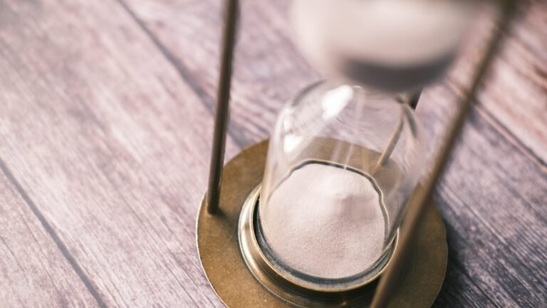 Close-up of an hourglass on a wooden surface.