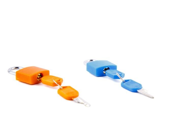 Orange and blue padlocks with matching keys on a white surface.