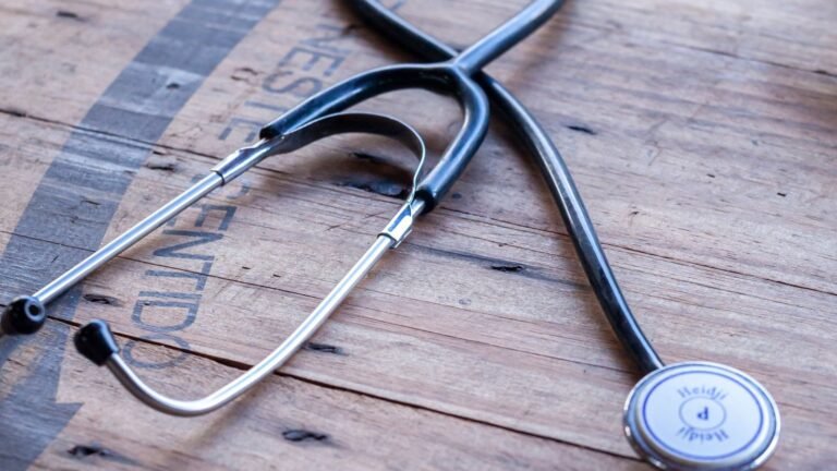Black and silver stethoscope resting on a wooden tabletop.