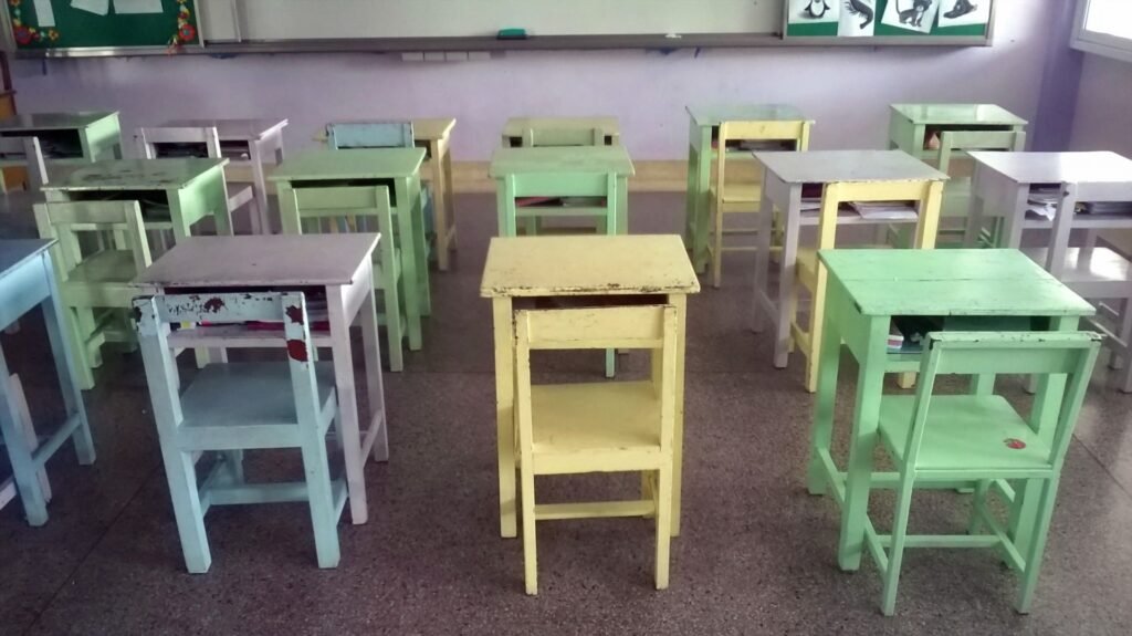 Pastel-colored wooden desks and chairs in an empty classroom.