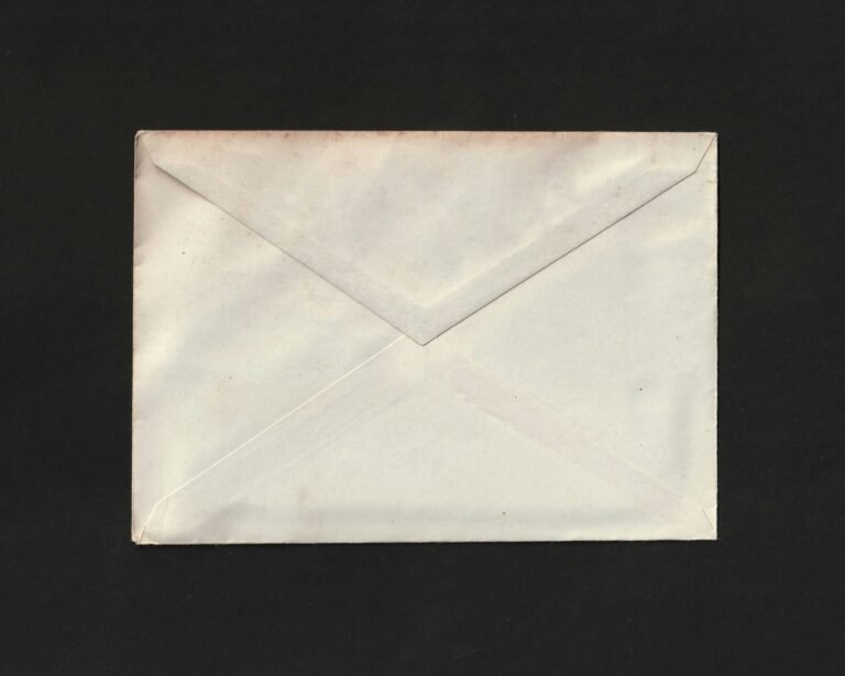 Back of a plain cream-colored envelope resting on a dark surface.