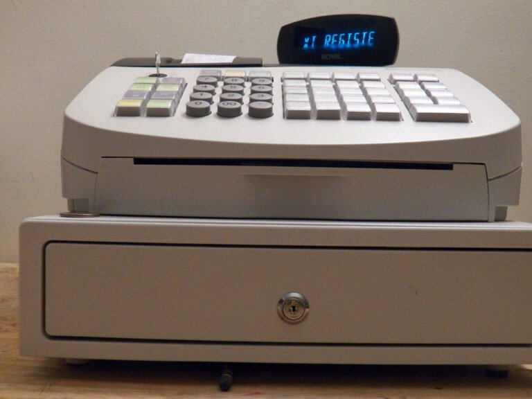 A beige cash register with numbered keys and a drawer.