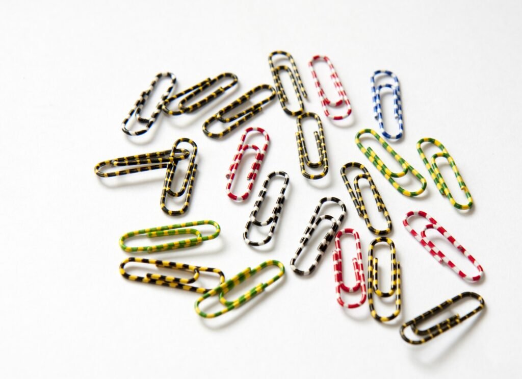 Colorful striped paper clips scattered on a white surface.