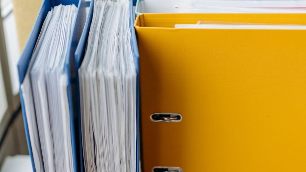 Blue document folders and a yellow binder holding stacks of papers.
