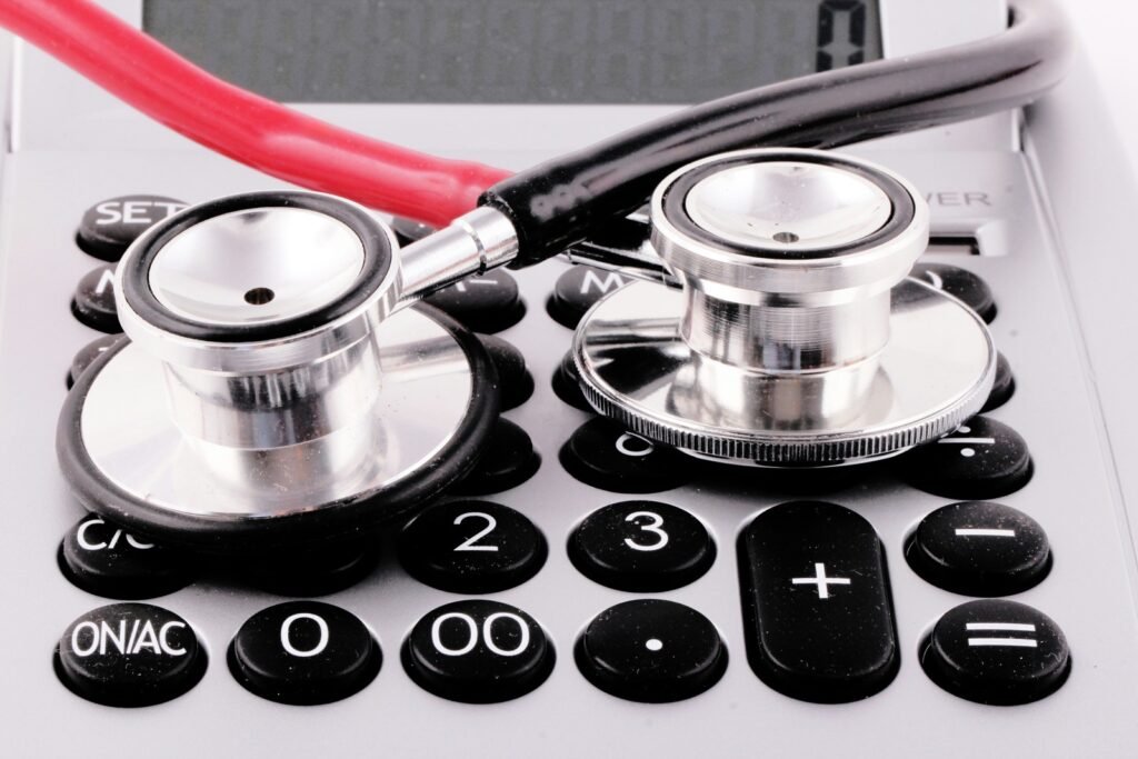 Two metal stethoscope heads with red and black tubing rest on a calculator.