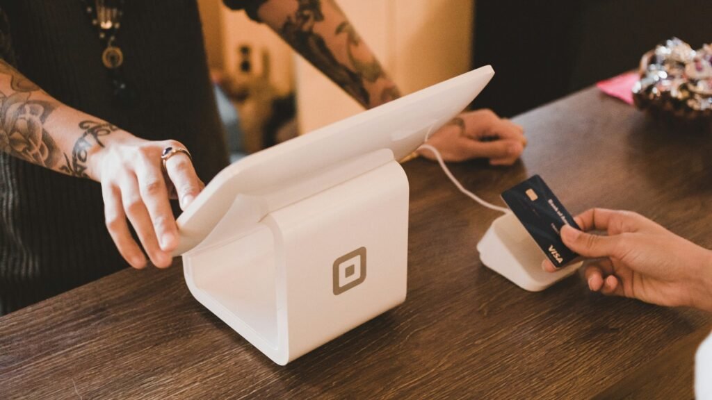 Close-up of hands using a payment card and point-of-sale terminal on a wooden counter.