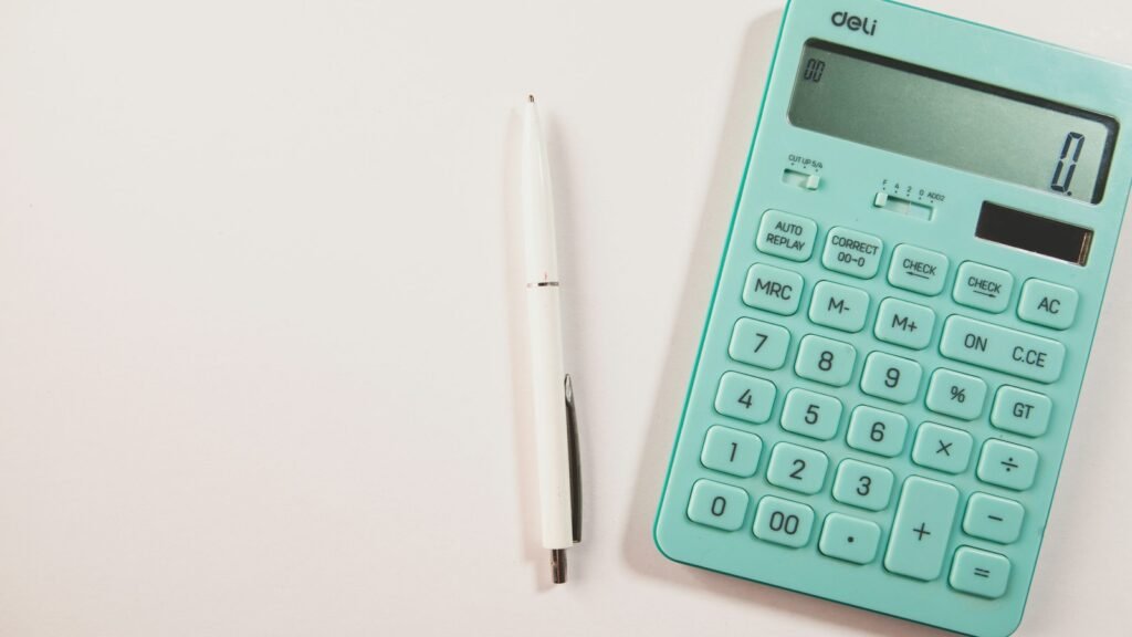 Teal calculator and a white pen on a pale surface.