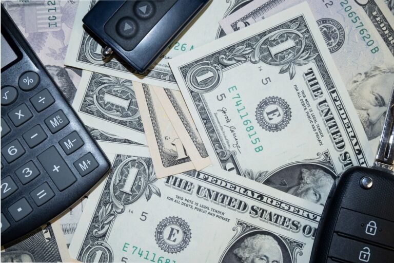 Car key fobs and part of a calculator rest on overlapping US dollar bills.