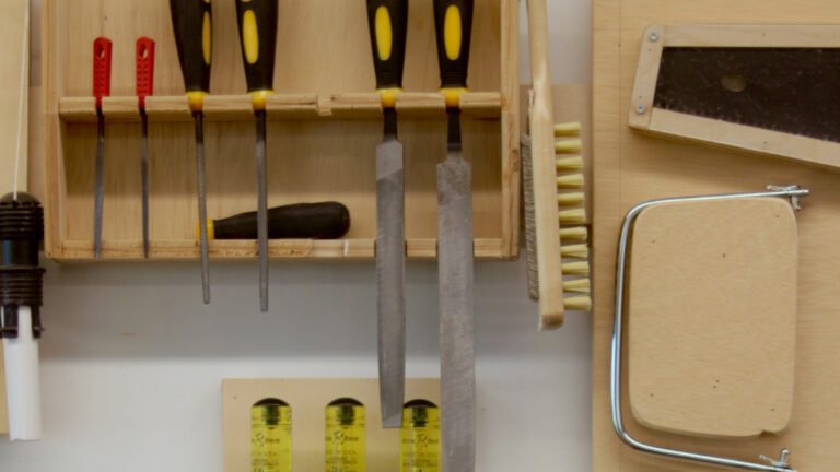 Woodworking files and saws hang in wooden wall-mounted racks.