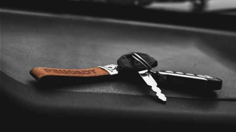 Car keys with a leather keychain rest on a dark surface.