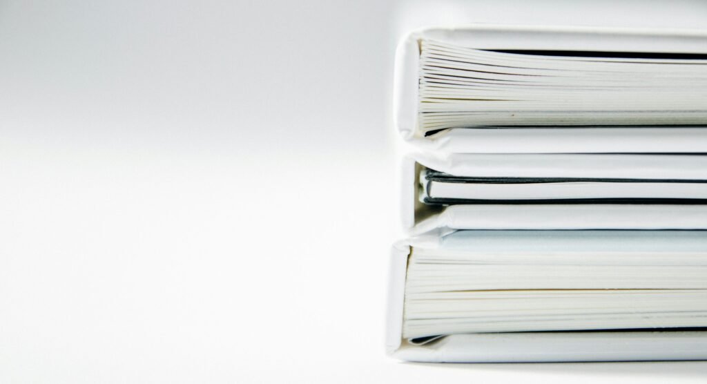 Three white folders stacked on a white surface.