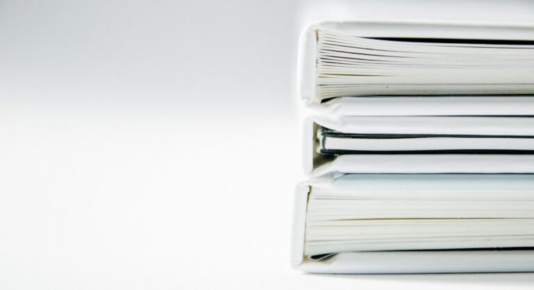 Three white folders stacked on a white surface.