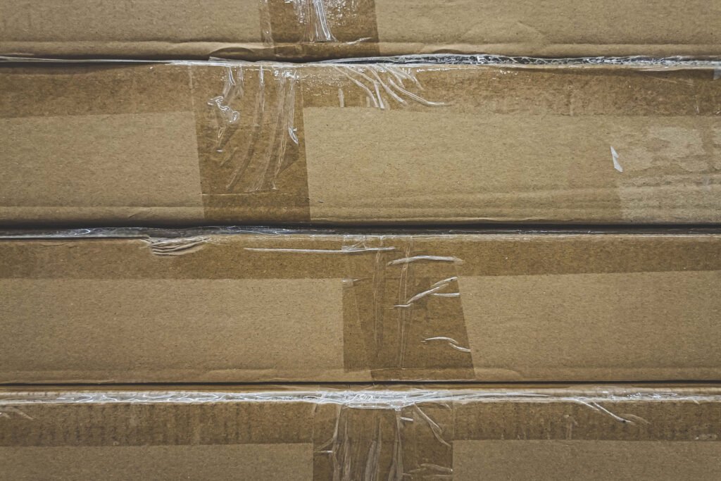 Close-up of stacked brown cardboard boxes sealed with clear packing tape.