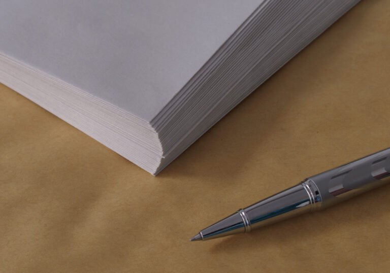A silver pen beside a stack of blank white envelopes.