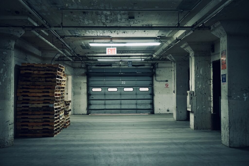 Stacked wooden pallets beside a closed loading door in a concrete warehouse interior.