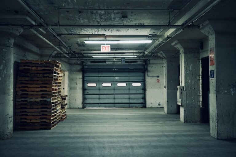 Stacked wooden pallets beside a closed loading door in a concrete warehouse interior.