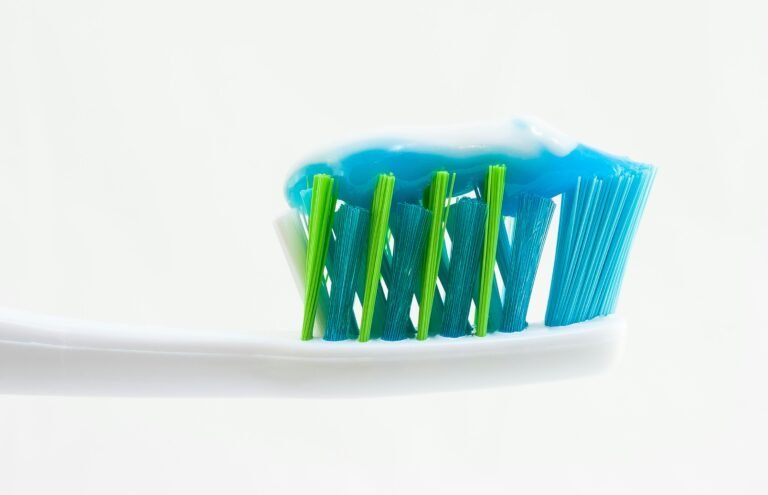Close-up of blue toothpaste on a toothbrush with blue and green bristles.