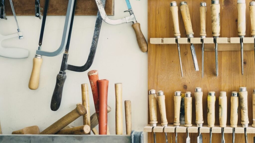 Saws and wood-handled chisels hang from racks on a workshop wall.